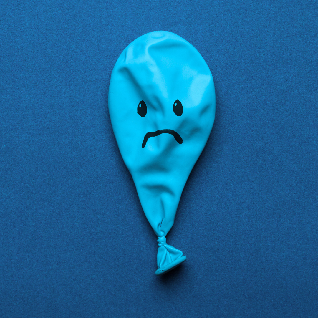 Flat balloon with a sad face drawn on
